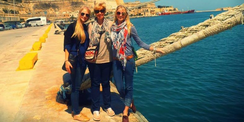 A family standing on the deck of a cruise ship, smiling and looking out at the ocean.
