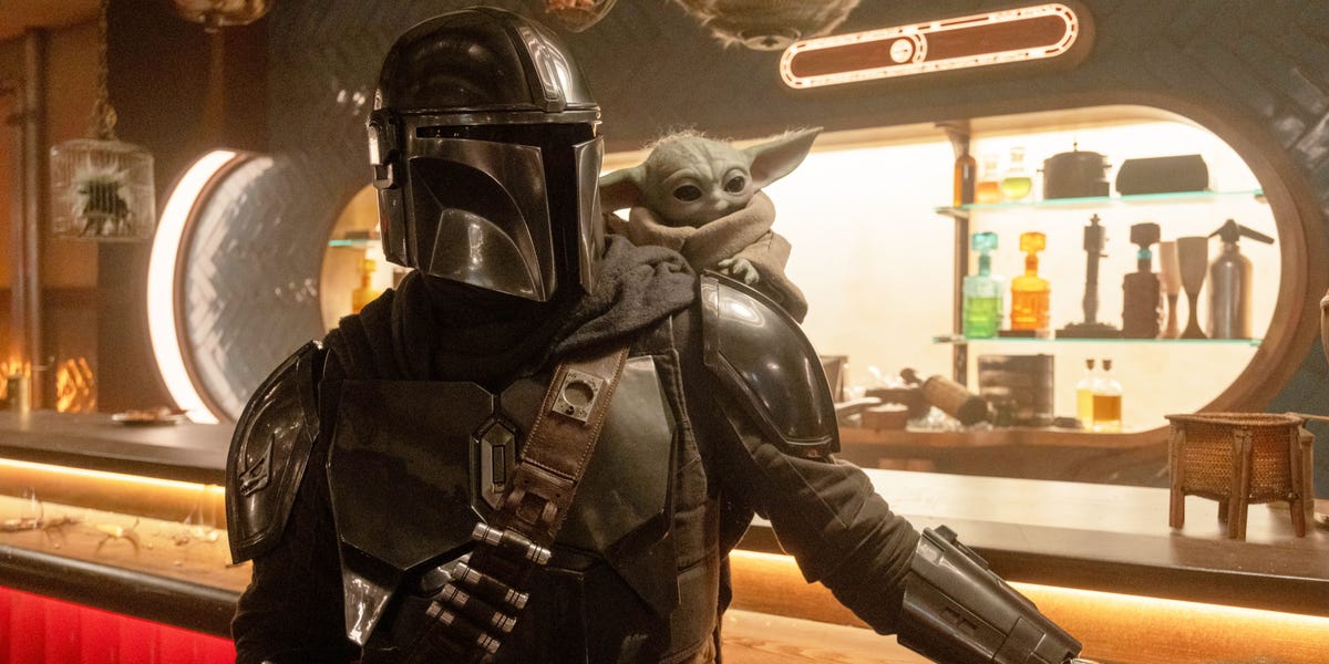The Mandalorian and Grogu characters standing together, with a galaxy background.