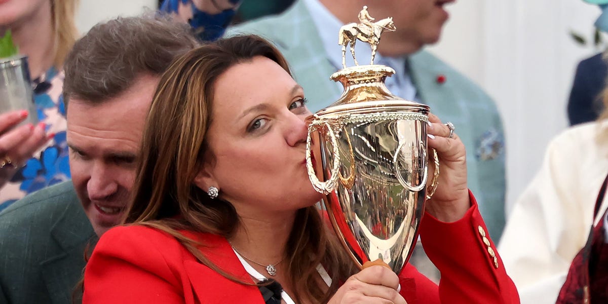 Cherie DeVaux smiling triumphantly with a trophy after winning the Kentucky Derby.