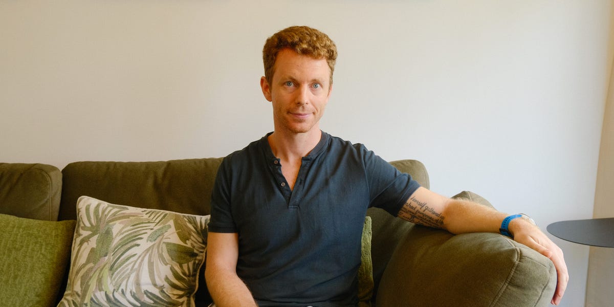 Nick Burns smiling in front of a modern apartment building in Singapore.