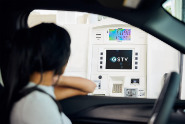 A person looking at a video screen while pumping gas