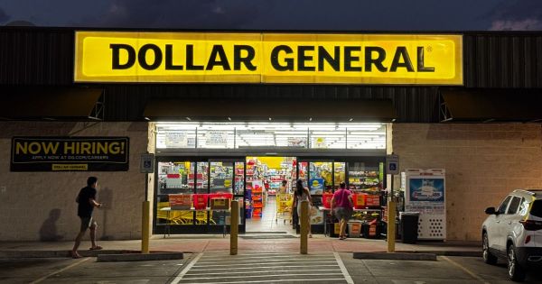 Aisle of a Dollar General store with a shopper pushing a cart.
